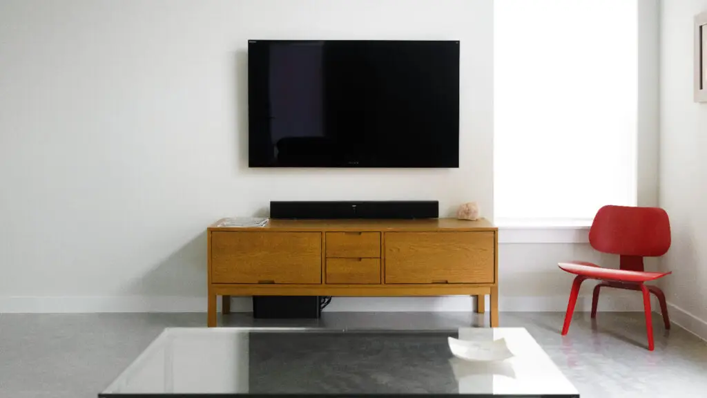 tv mounted over a wooden tv stand.