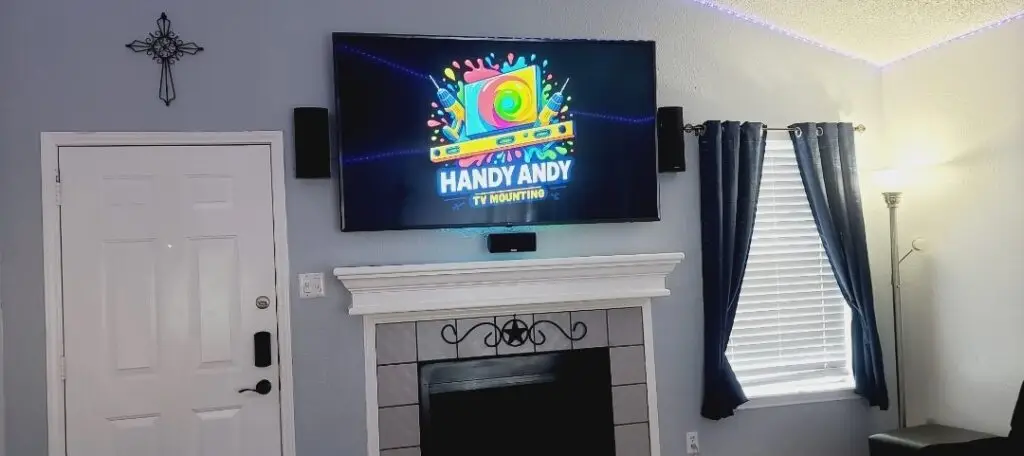 Tv mounted over a fireplace in austin. Tv has handy andy tv mounting logo on it.