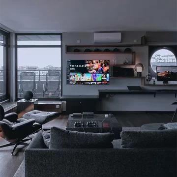 TV on wall with shelves around it. Dark living room